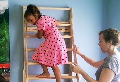 Girl climbing down ladder guided by therapist