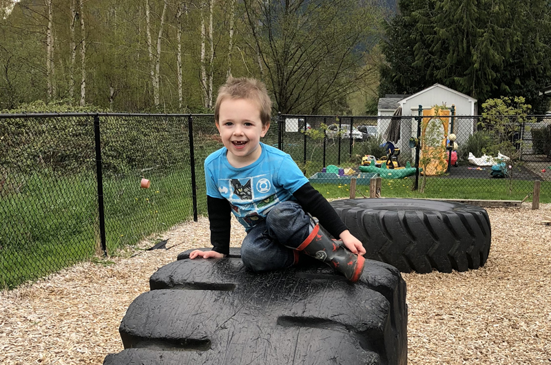 Little boy playing on a big tire