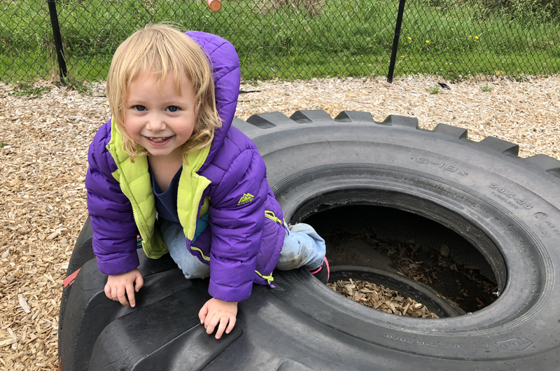 Little girl playing on a big tire