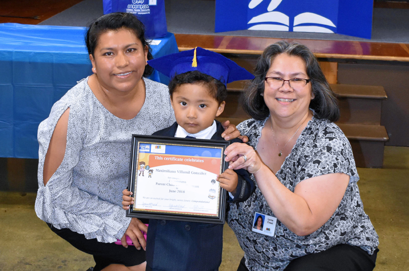 Little boy poses with graduation certificate