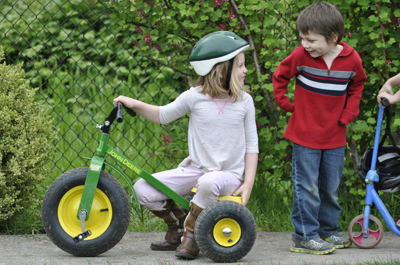 Children ride tricycles together