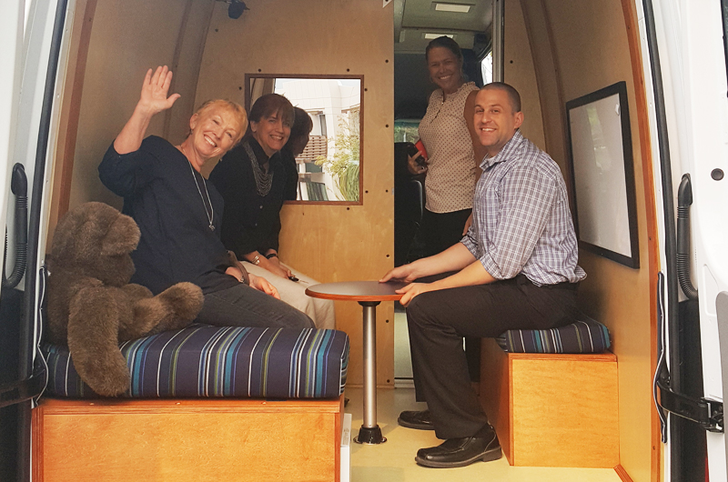 A group of people sitting inside the back of the Mobile Therapy Unit