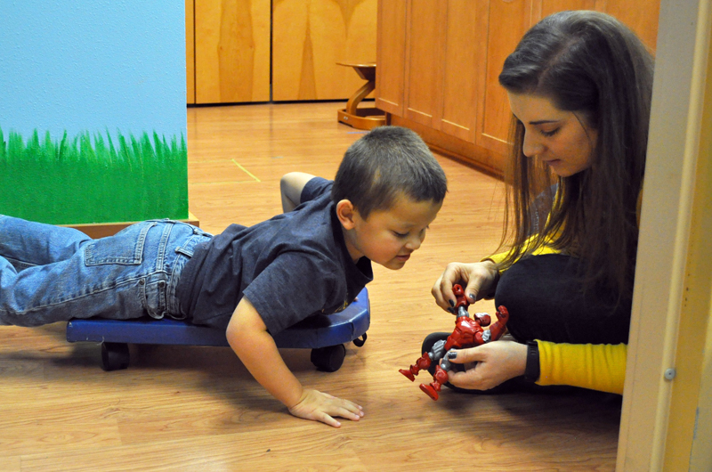 Boy working with therapist to put together a toy