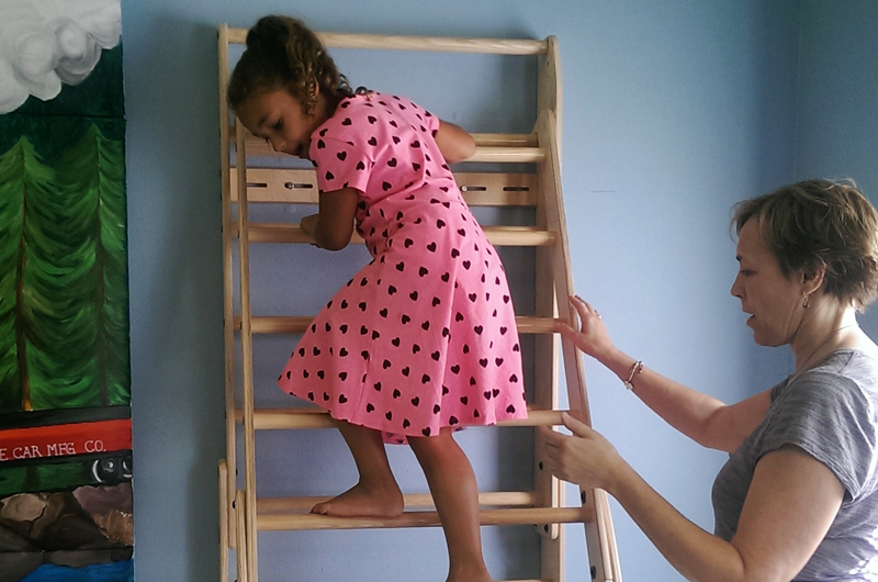 Girl climbing down ladder assisted by occupational therapist