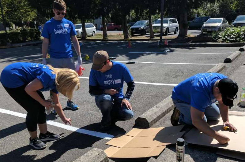 Group of volunteers painting parking lot spaces