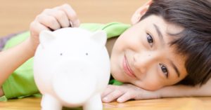 Little boy putting a coin into a piggy bank