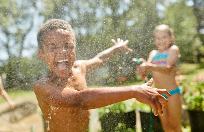 Two children play with a hose outside