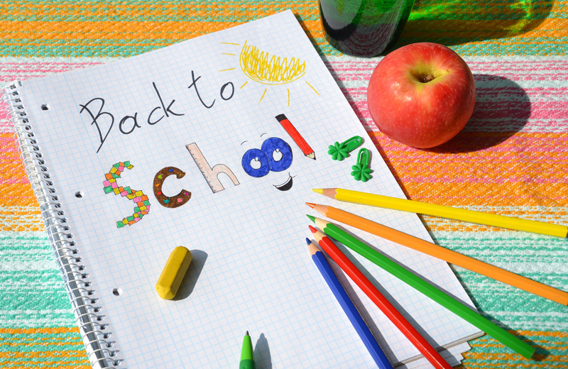 Back to school written on a notebook with colored pencils