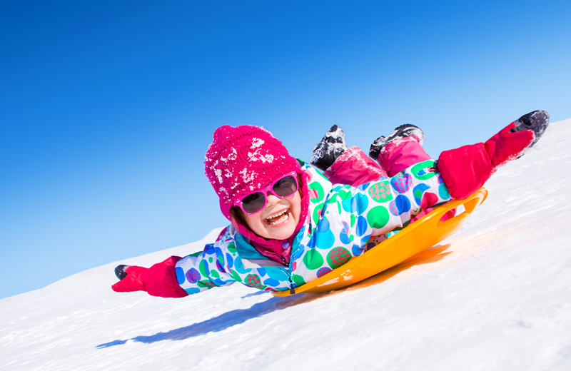 Little girl sledding on her tummy