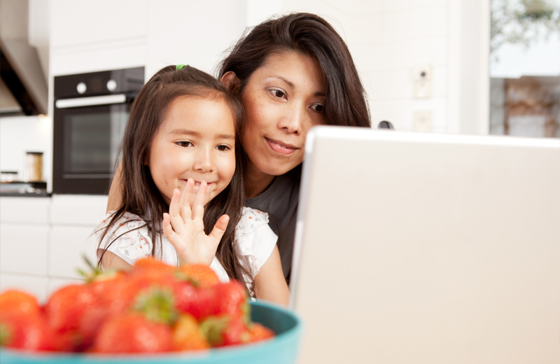 Little girl and mom video chatting on laptop