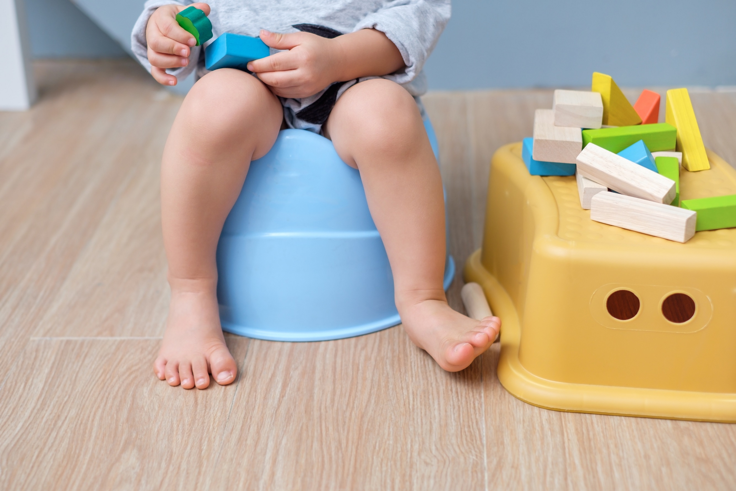 Child on toddler toilet with toys next to it