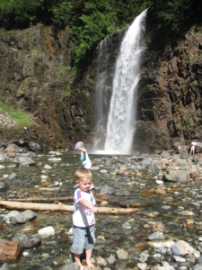 small boy in front of a waterfall