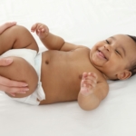 Smiling baby getting legs massaged