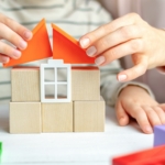 hands building a toy house