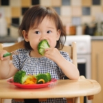 little girl eating broccoli